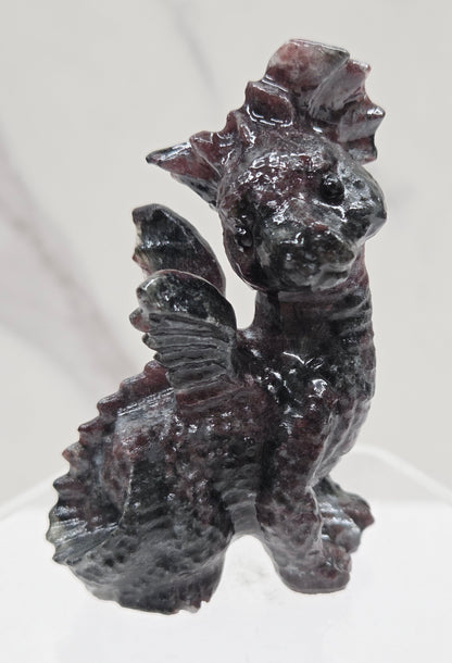Garnet dragon carving on an acrylic stand against a neutral background
