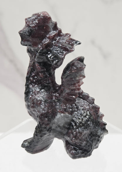 Garnet dragon carving on an acrylic stand against a neutral background
