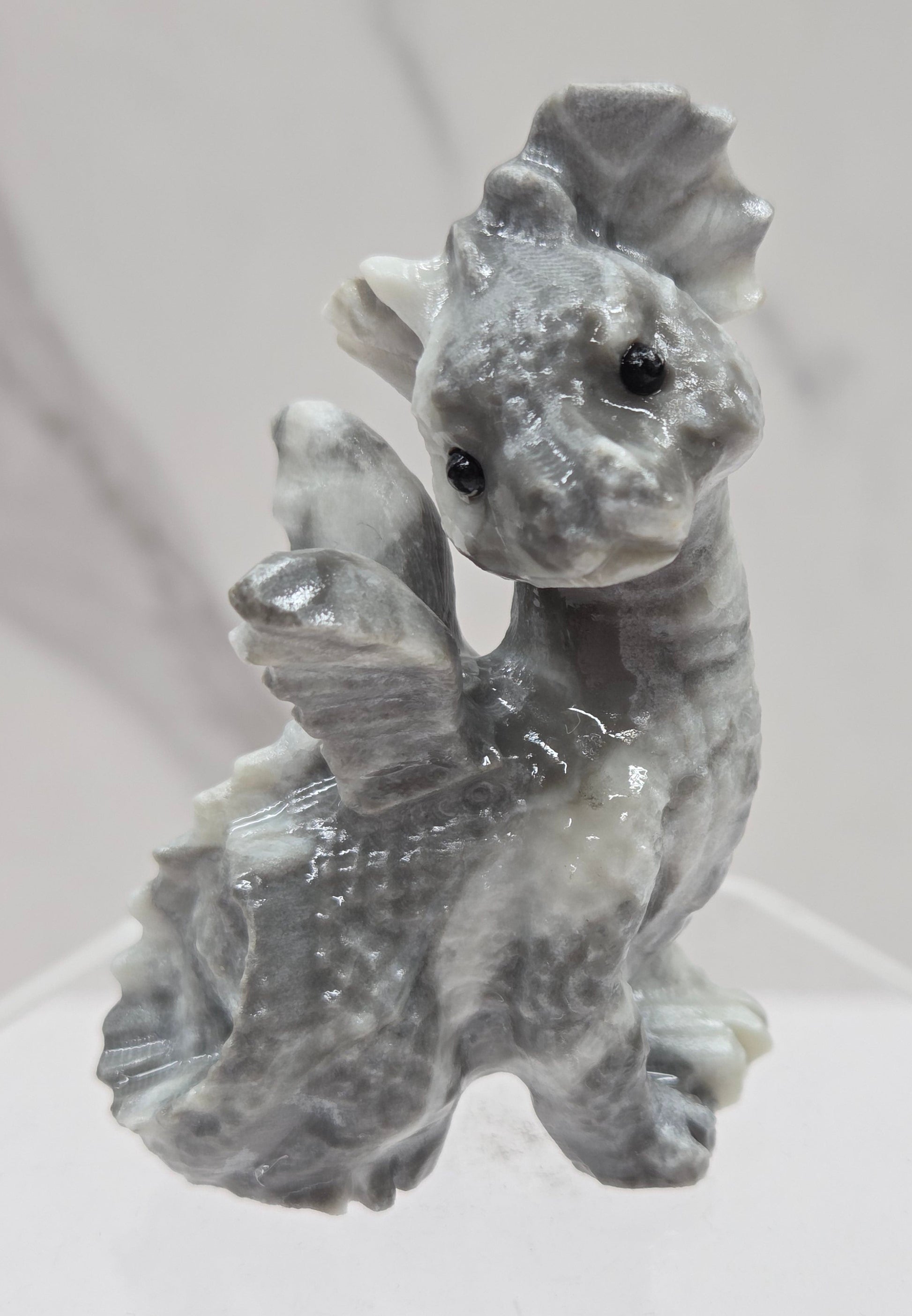 Grey & white crystal dragon carving on an acrylic stand against a neutral background