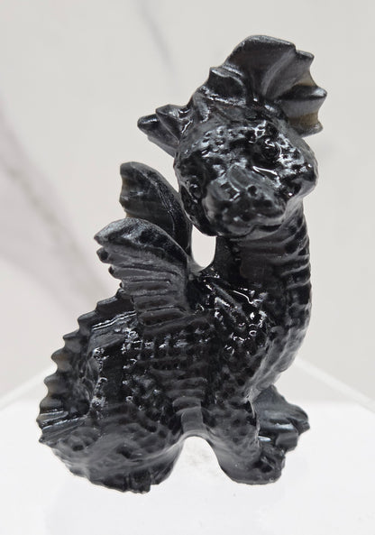 Obsidian dragon carving on an acrylic stand against a neutral background