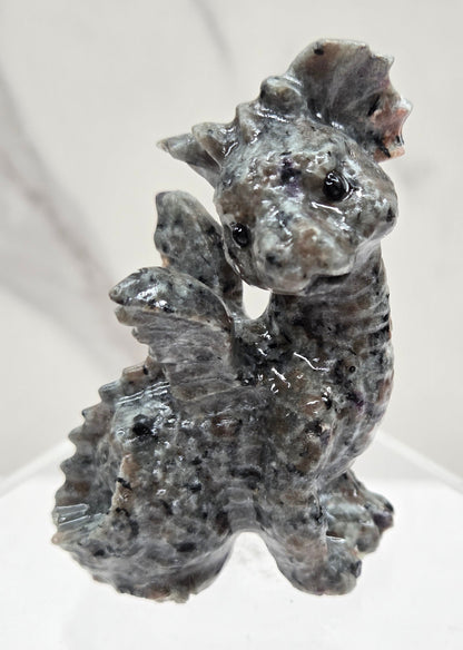 Yooperlite dragon carving on an acrylic stand against a neutral background