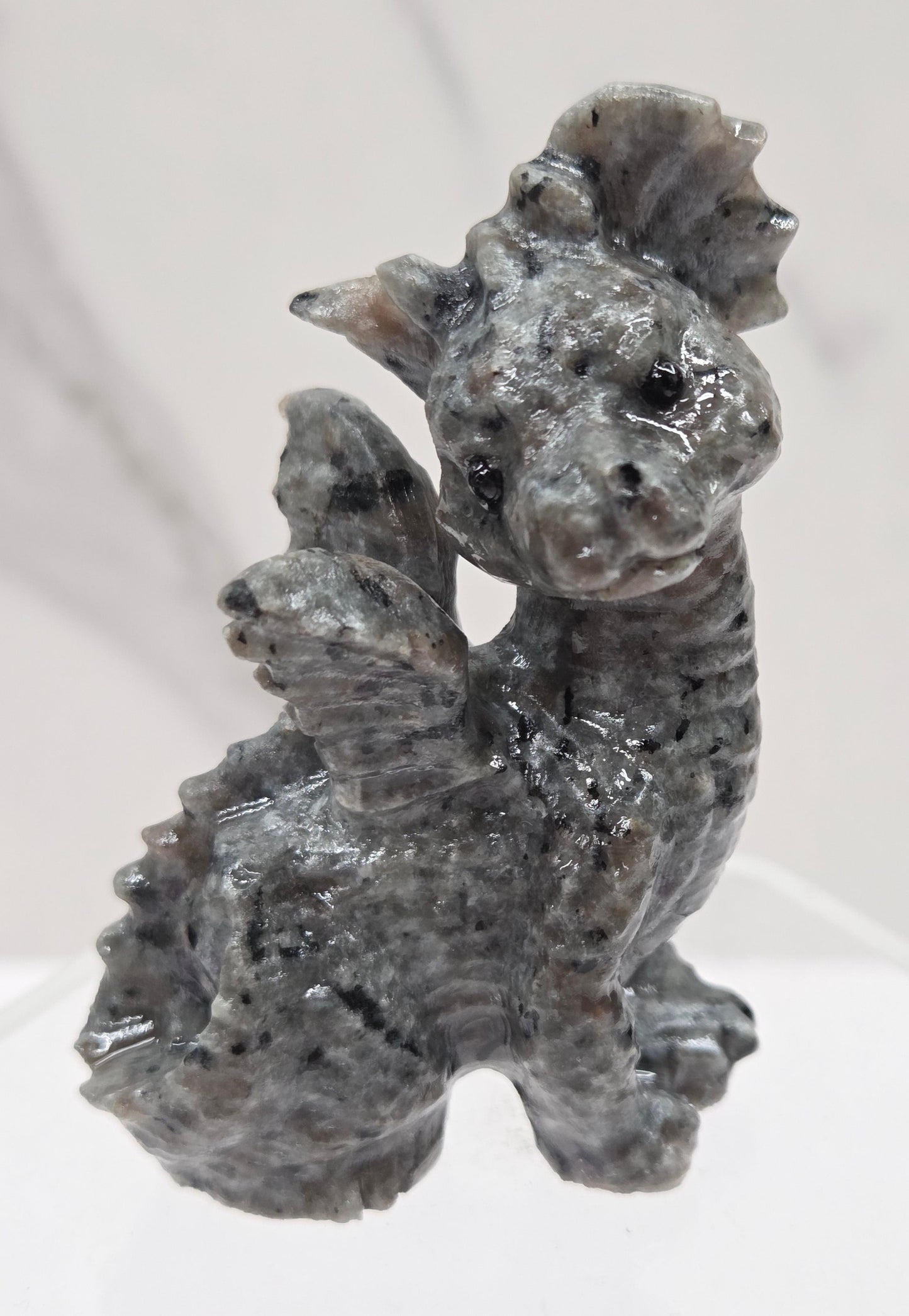 Yooperlite dragon carving on an acrylic stand against a neutral background
