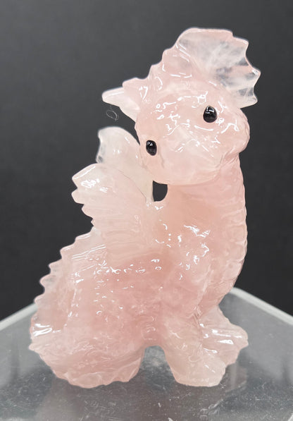 Rose Quartz dragon carving on an acrylic stand against a neutral background