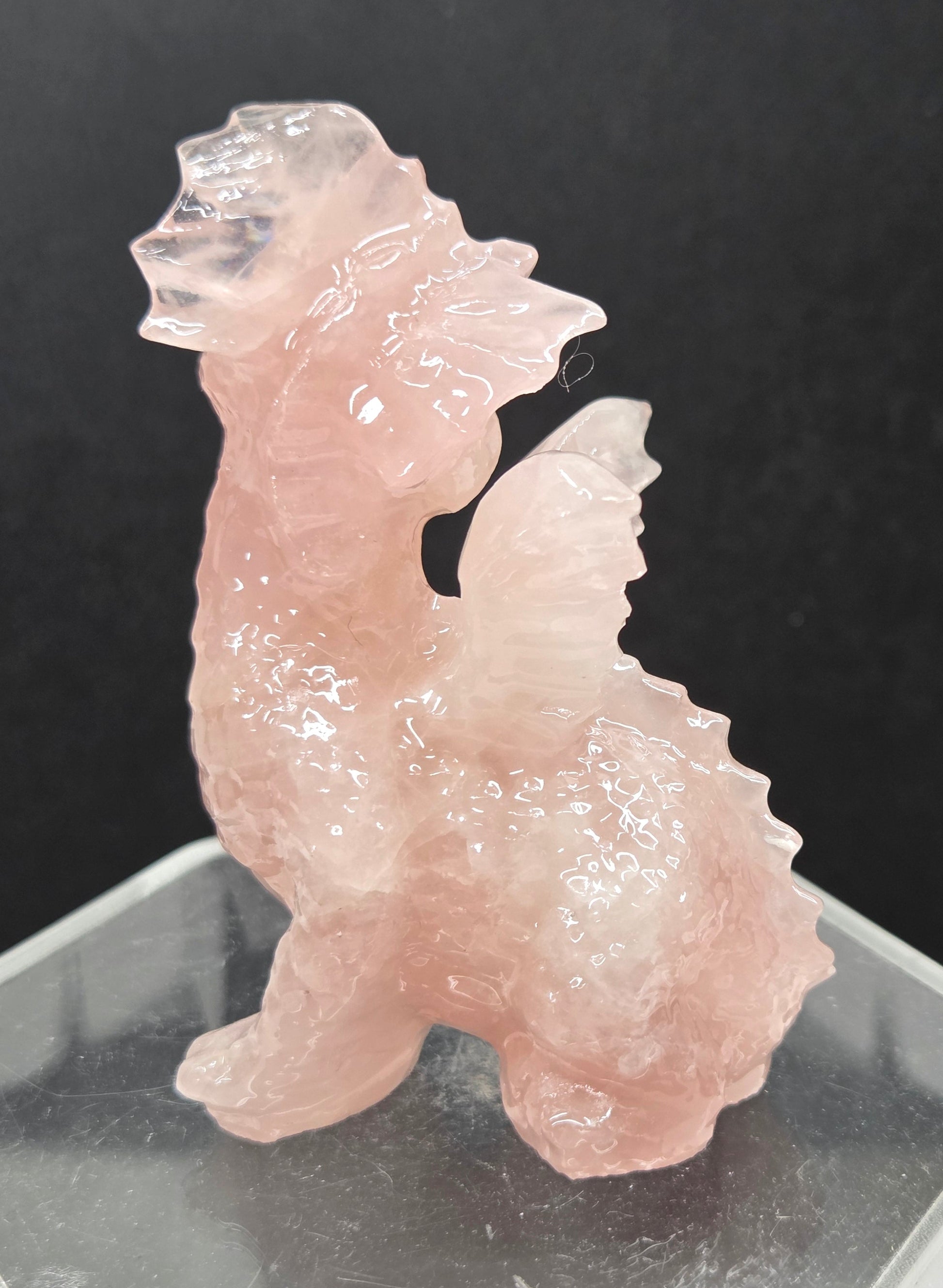 Rose Quartz dragon carving on an acrylic stand against a neutral background