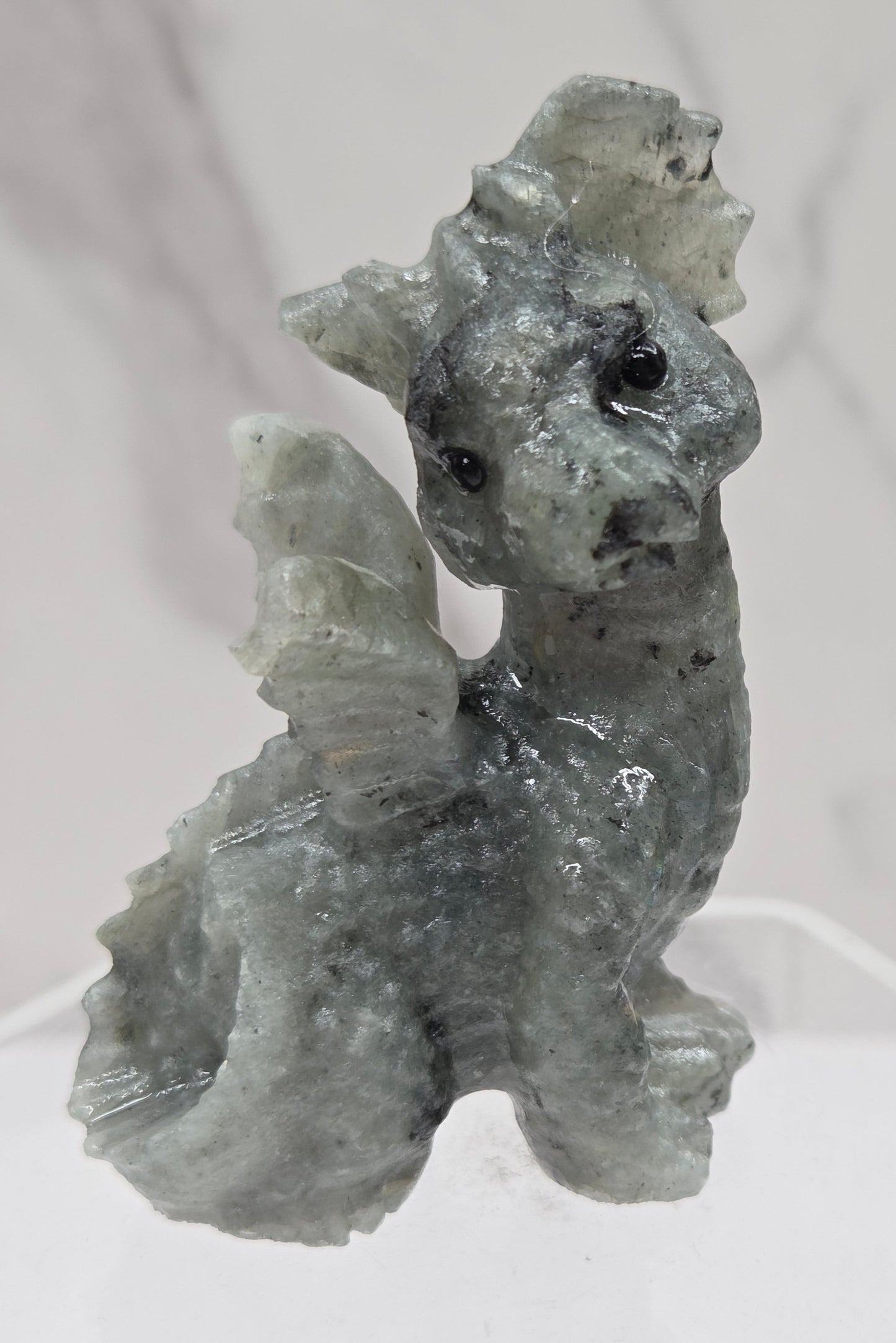 Labradorite dragon carving on an acrylic stand against a neutral background