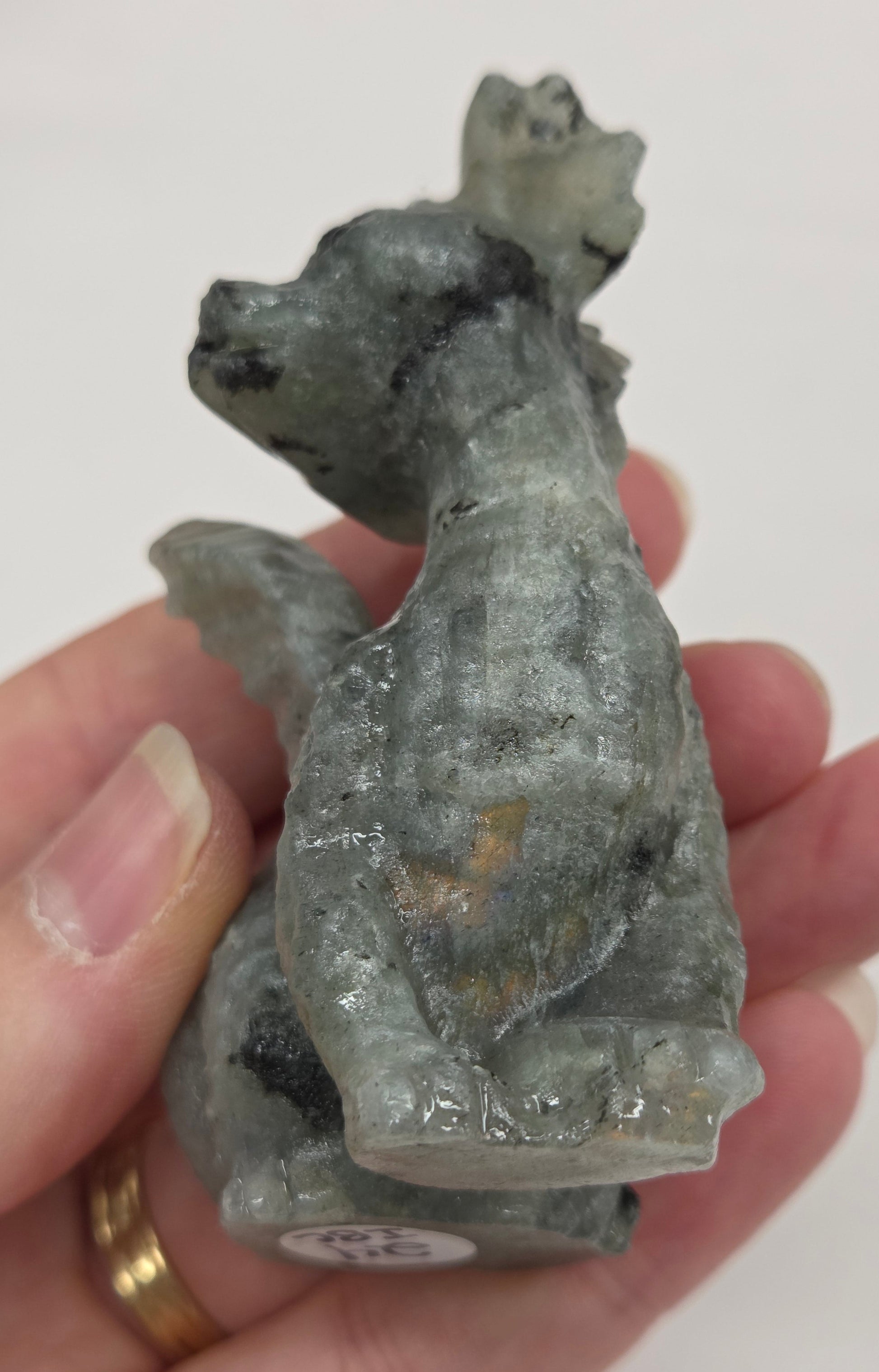 Hand holding a Labradorite dragon carving against a neutral background