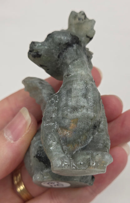 Hand holding a Labradorite dragon carving against a neutral background