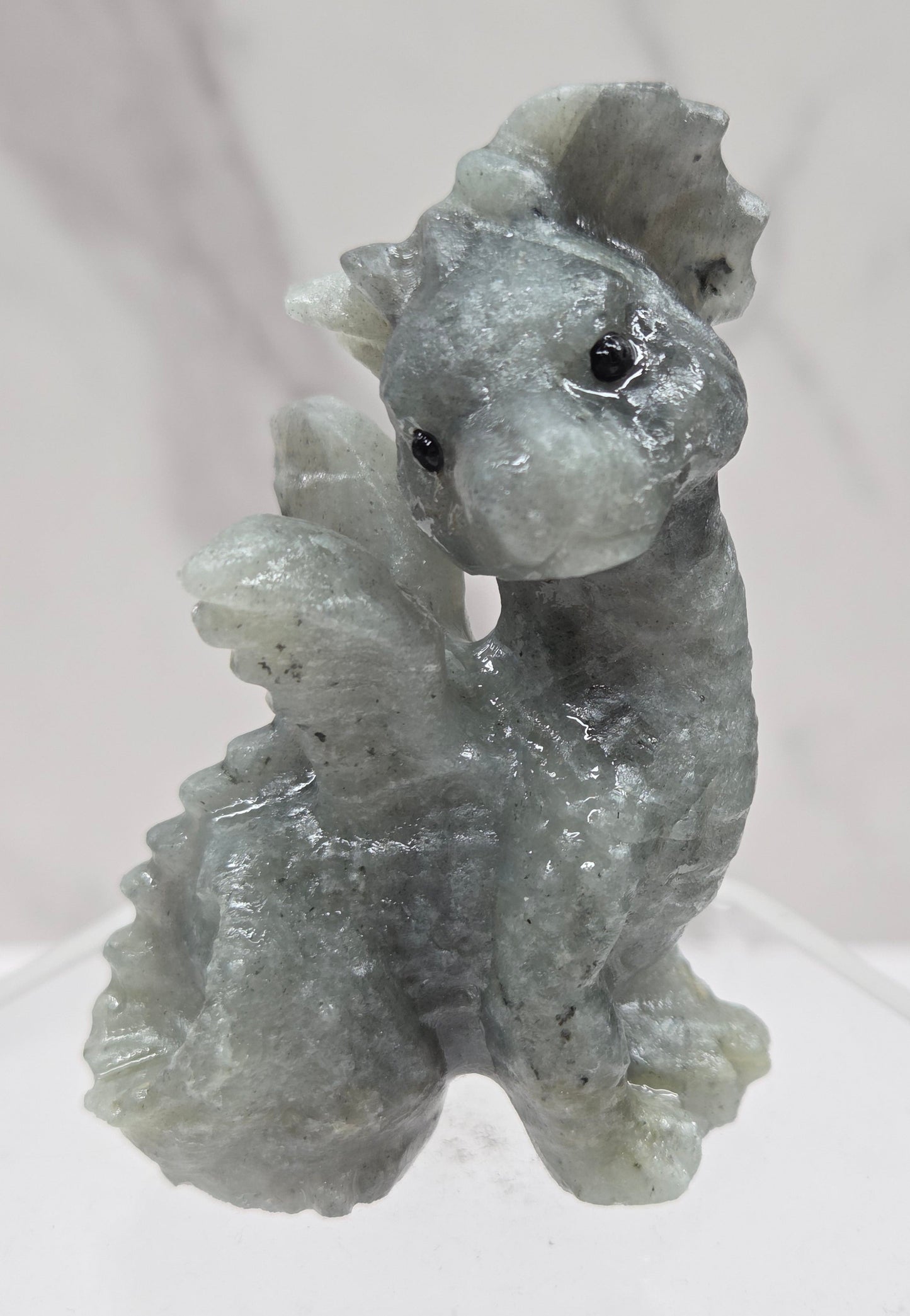 Labradorite dragon carving on an acrylic stand against a neutral background