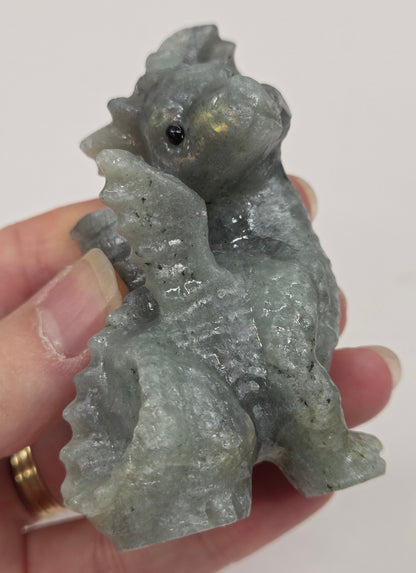 Hand holding a Labradorite dragon carving against a neutral background