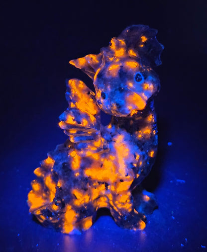 Yooperlite dragon carving against a neutral background under UV light