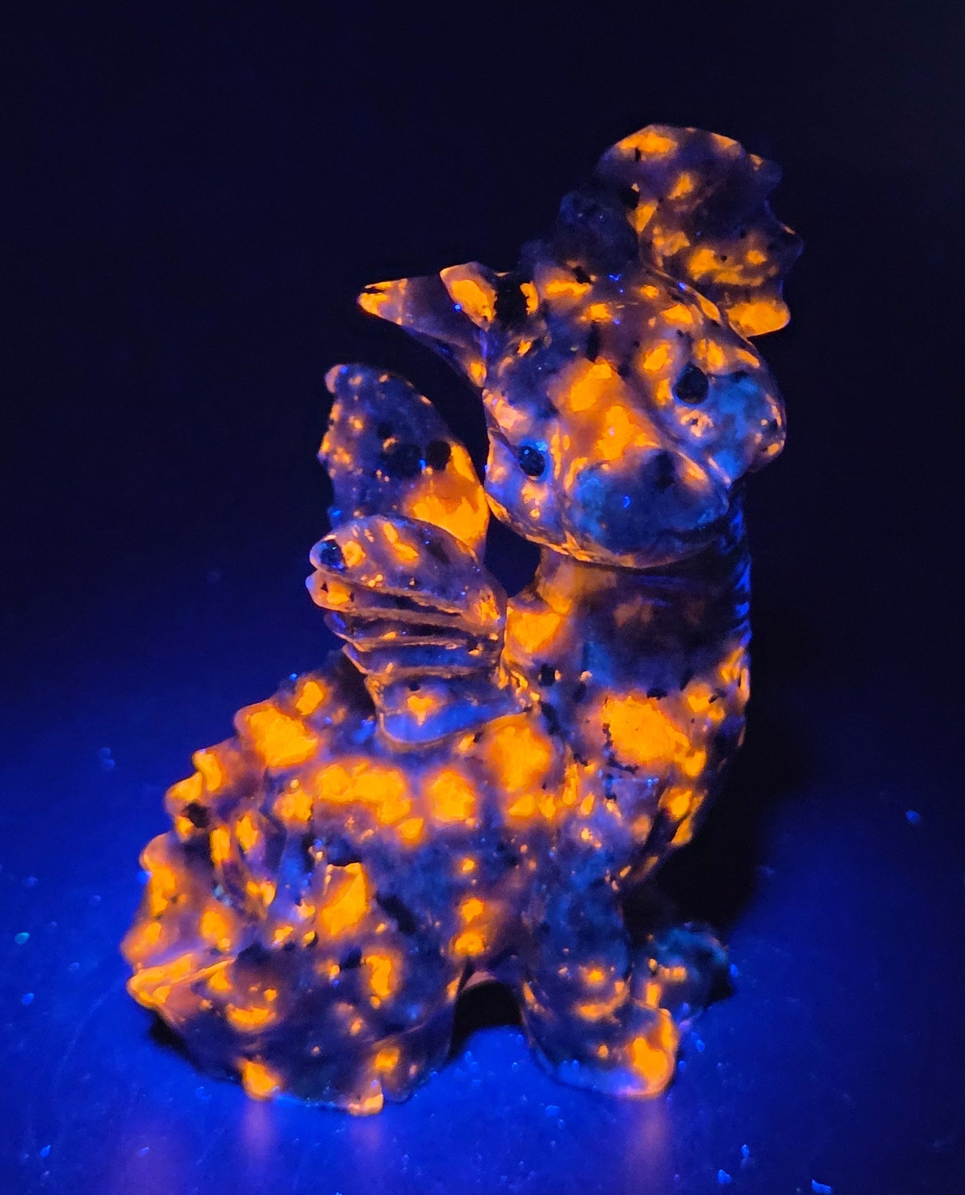 Yooperlite dragon carving against a neutral background under UV light
