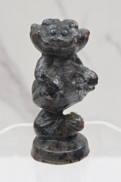 Cheshire Cat carving made of Yooperlite on a clear stand against a neutral background