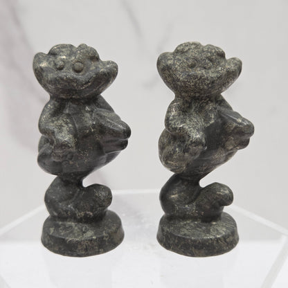 Cheshire Cat carvings made of Pyrite on a clear stand against a neutral background