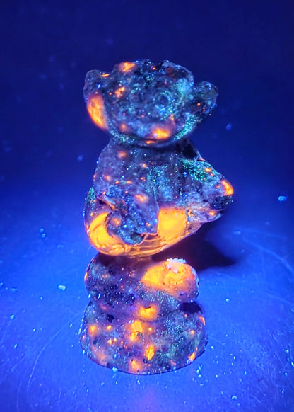 Cheshire Cat carving made of Yooperlite  against a neutral background under UV light