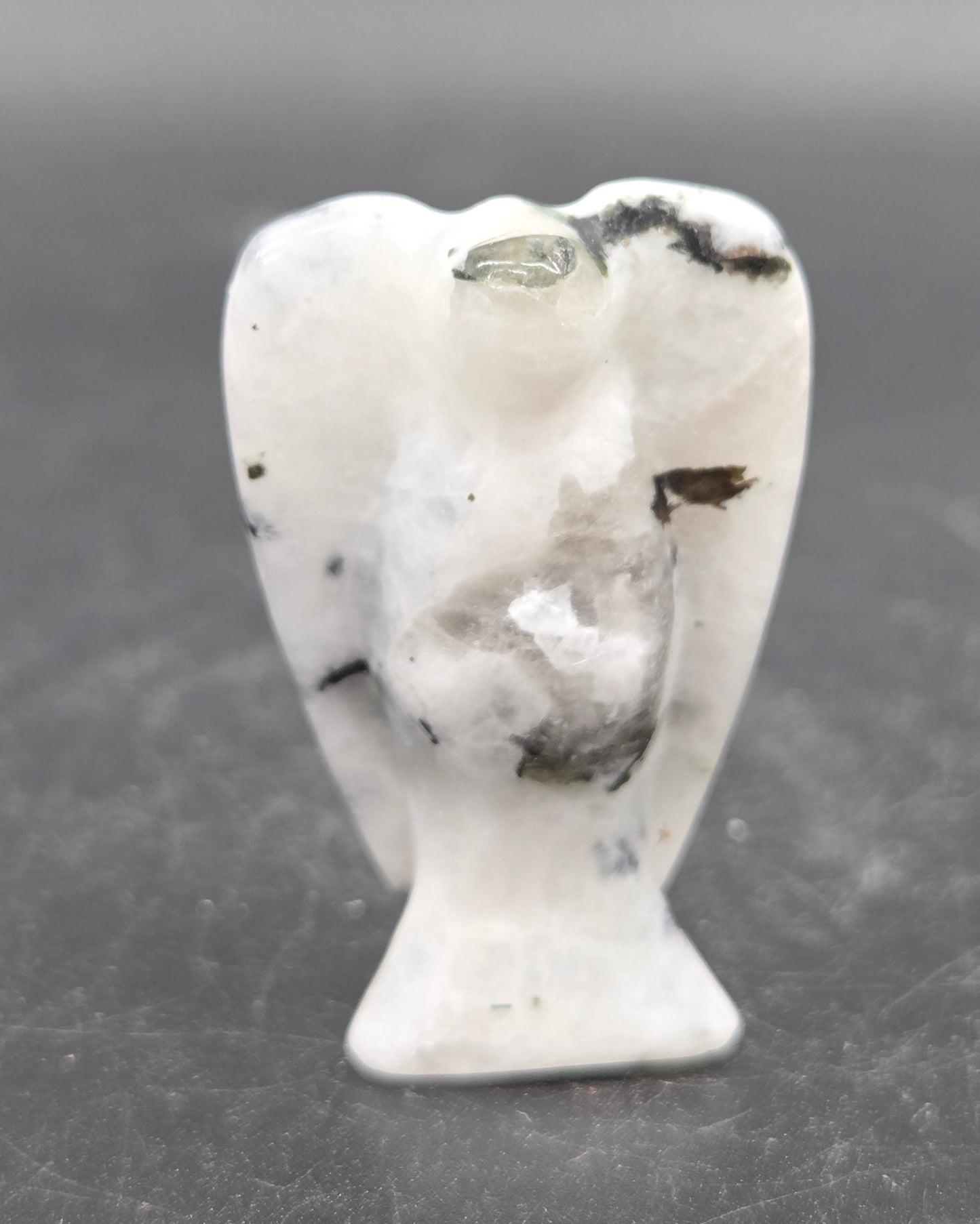 Small white angel figurine on a dark gray background