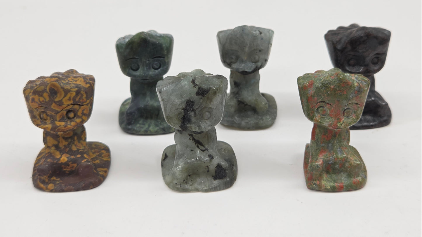 Set of six small stone Groot sculptures on a white background