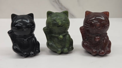 Three cat-shaped figurines in black, green, and brown on a white background