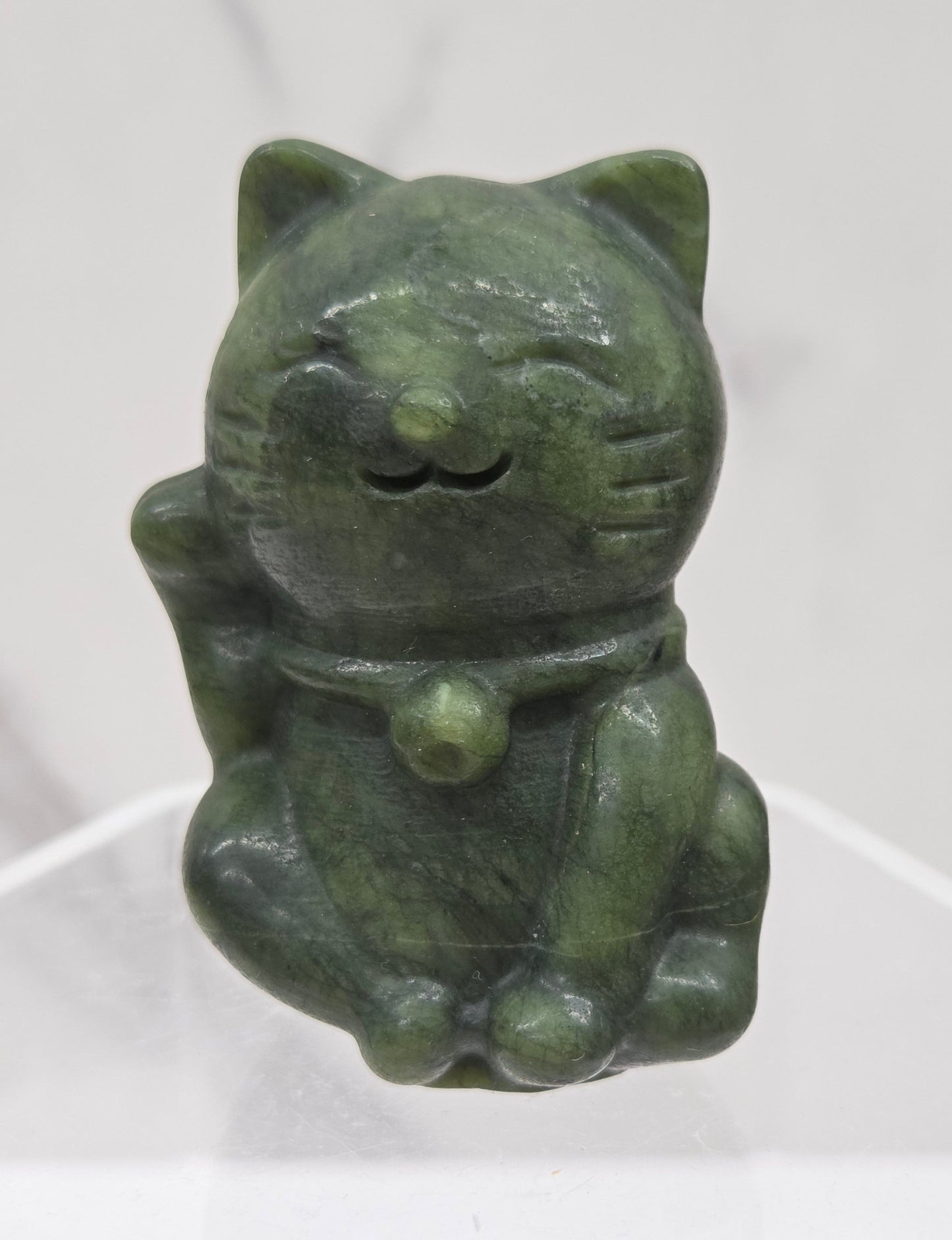 Green stone sculpture of a cat on a white background