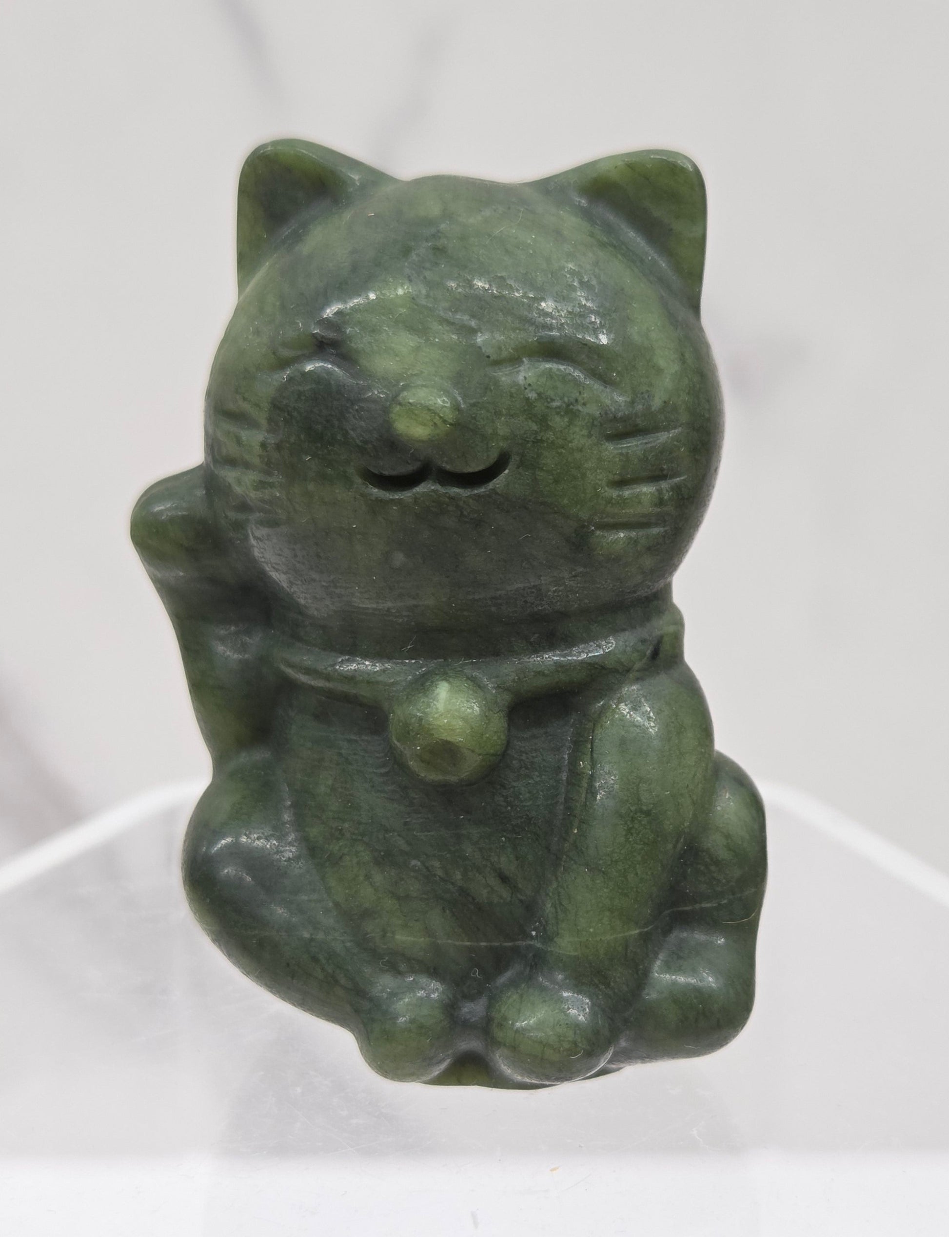 Green stone sculpture of a cat on a white background