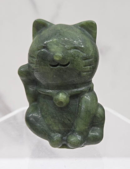 Green stone sculpture of a cat on a white background