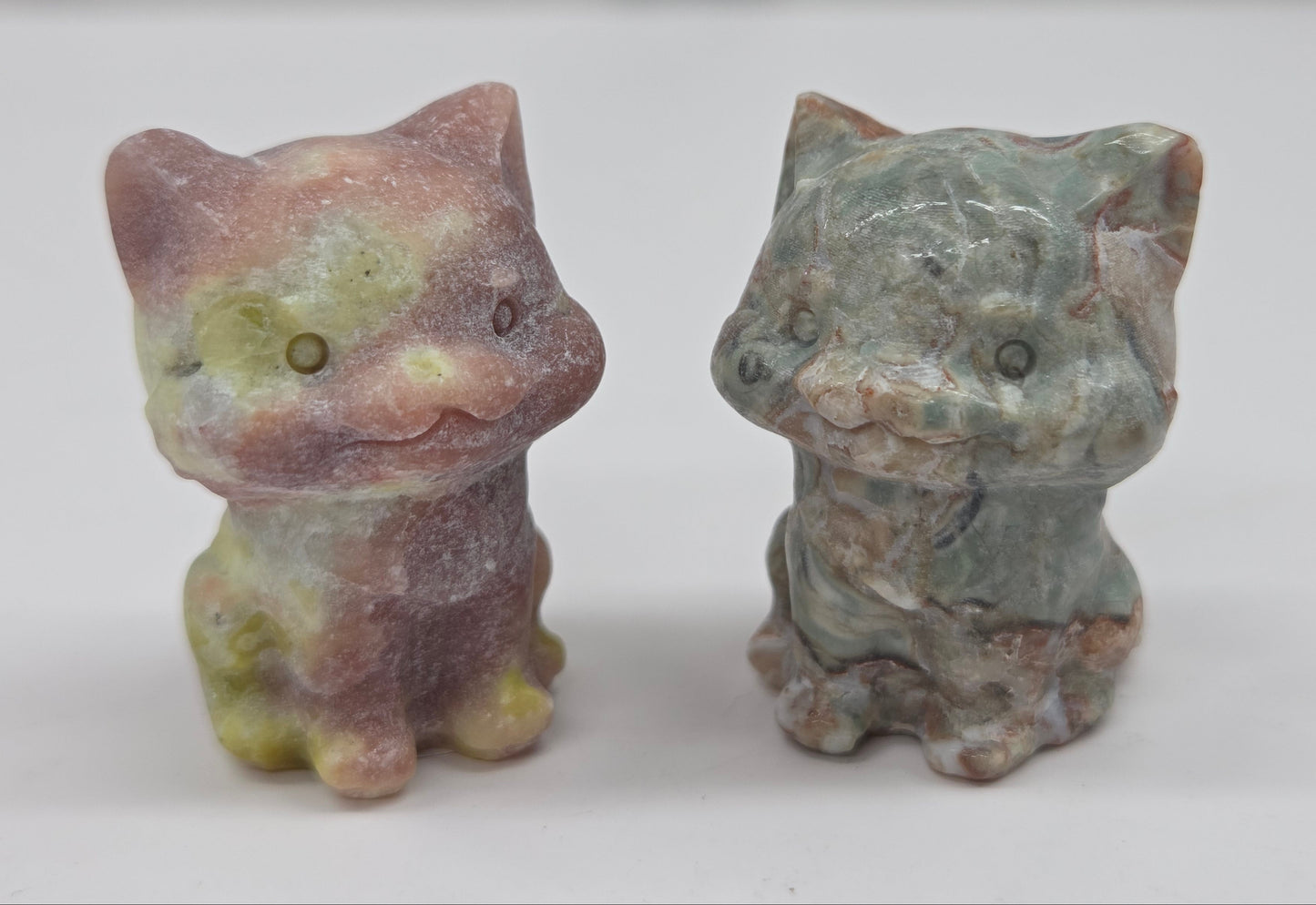 Two small stone cat figurines on a white background