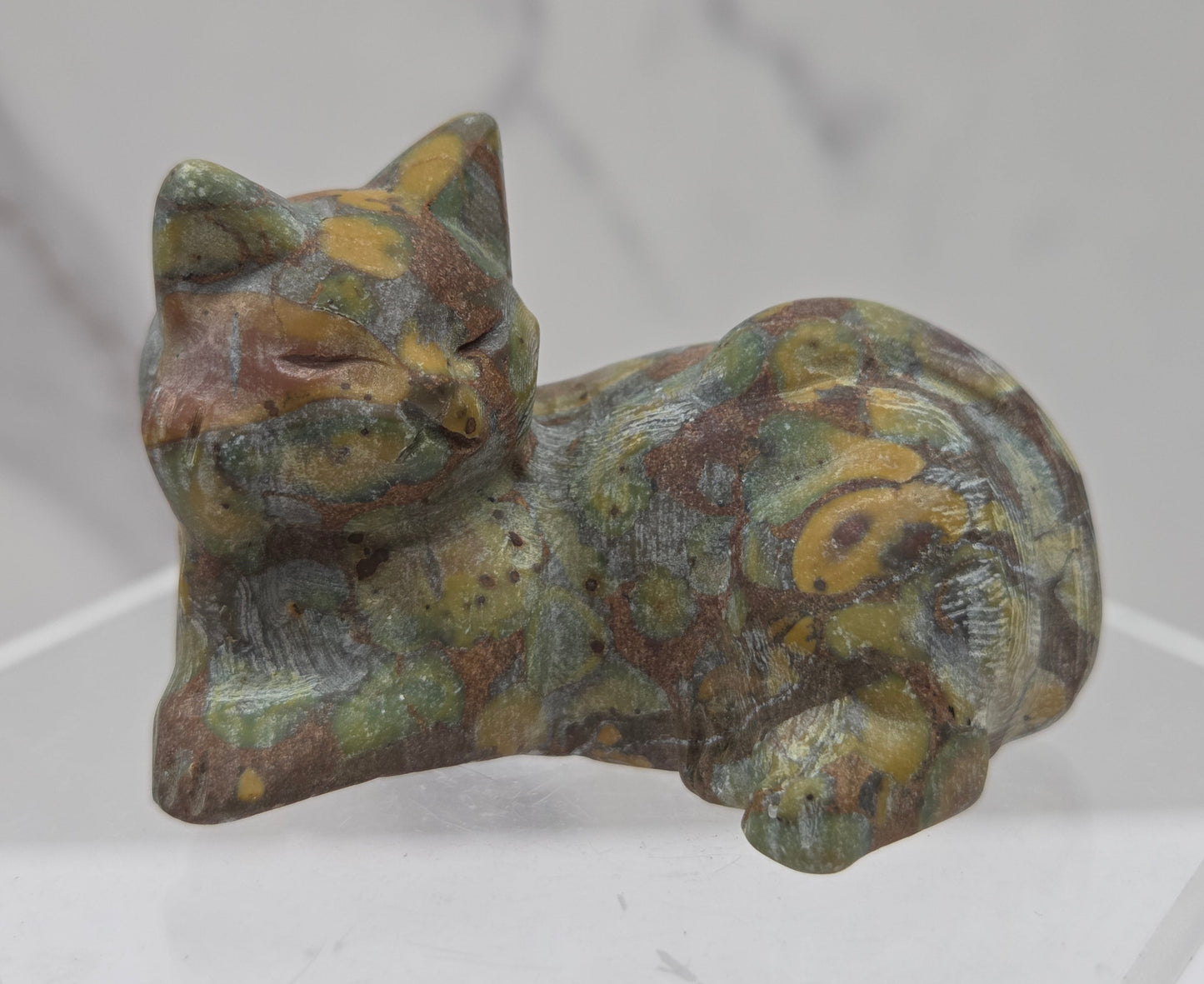 Ajooba Jasper cat carving lying down an acrylic stand against a neutral background