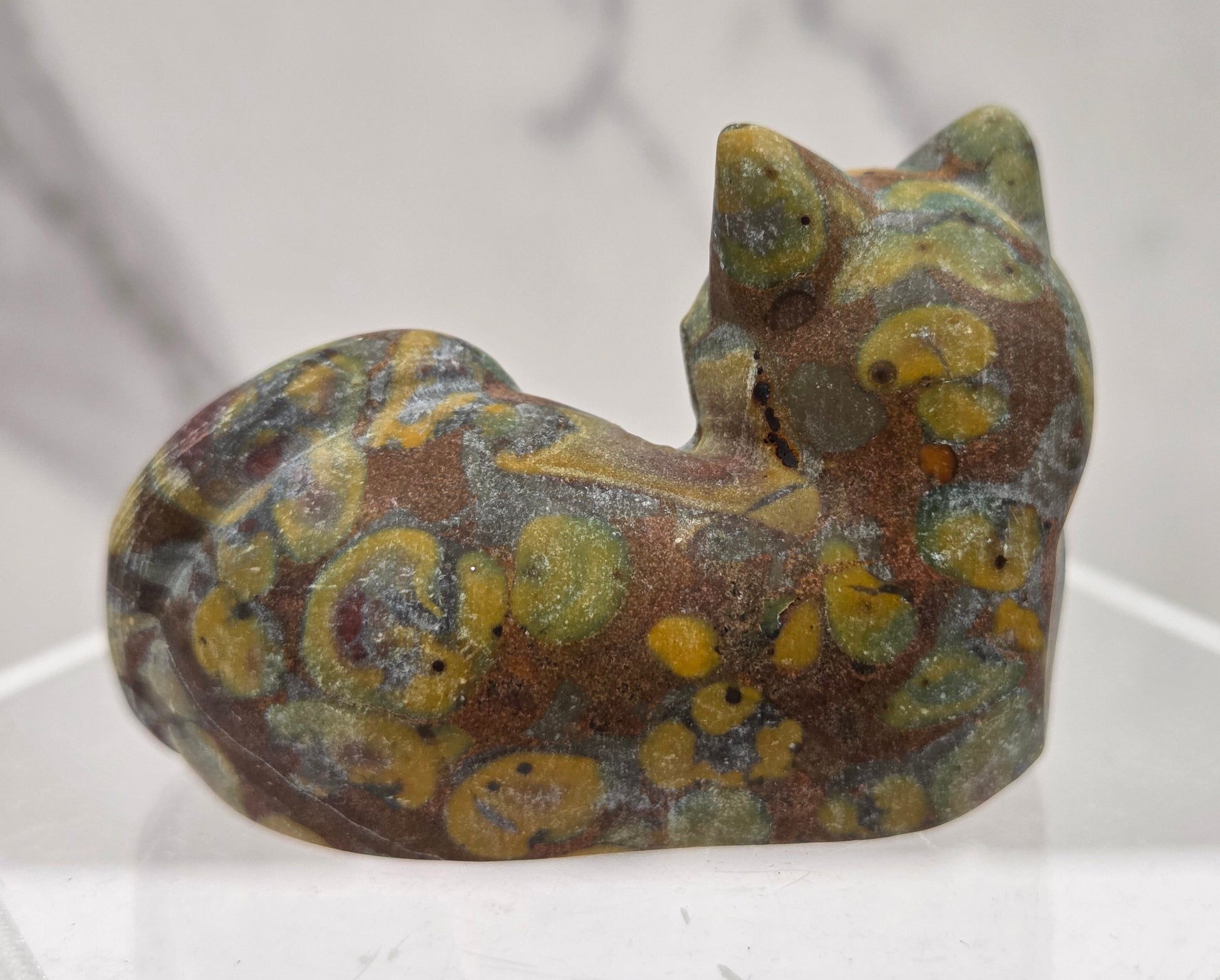 Ajooba Jasper cat carving lying down an acrylic stand against a neutral background