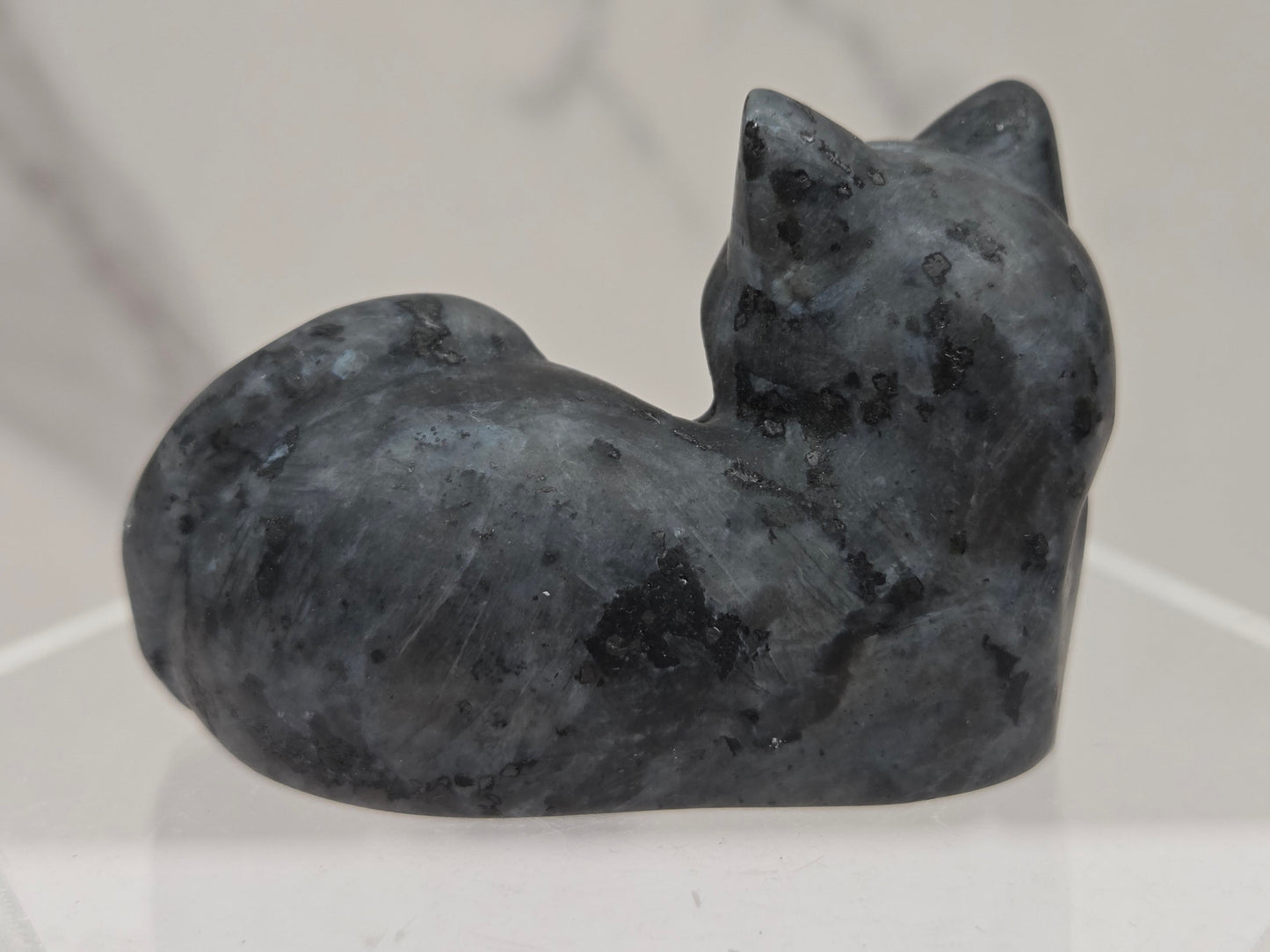 Larvikite cat carving lying down an acrylic stand against a neutral background