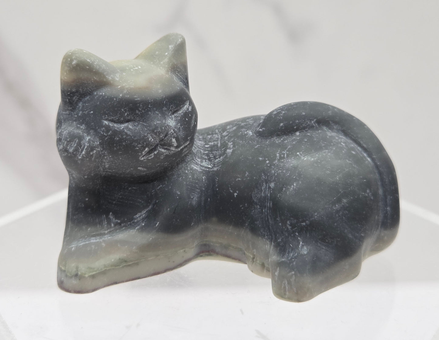 Jasper cat carving lying down an acrylic stand against a neutral background