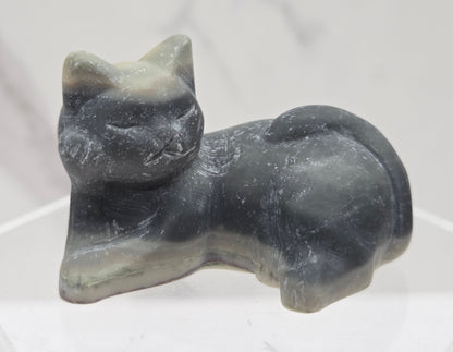 Jasper cat carving lying down an acrylic stand against a neutral background