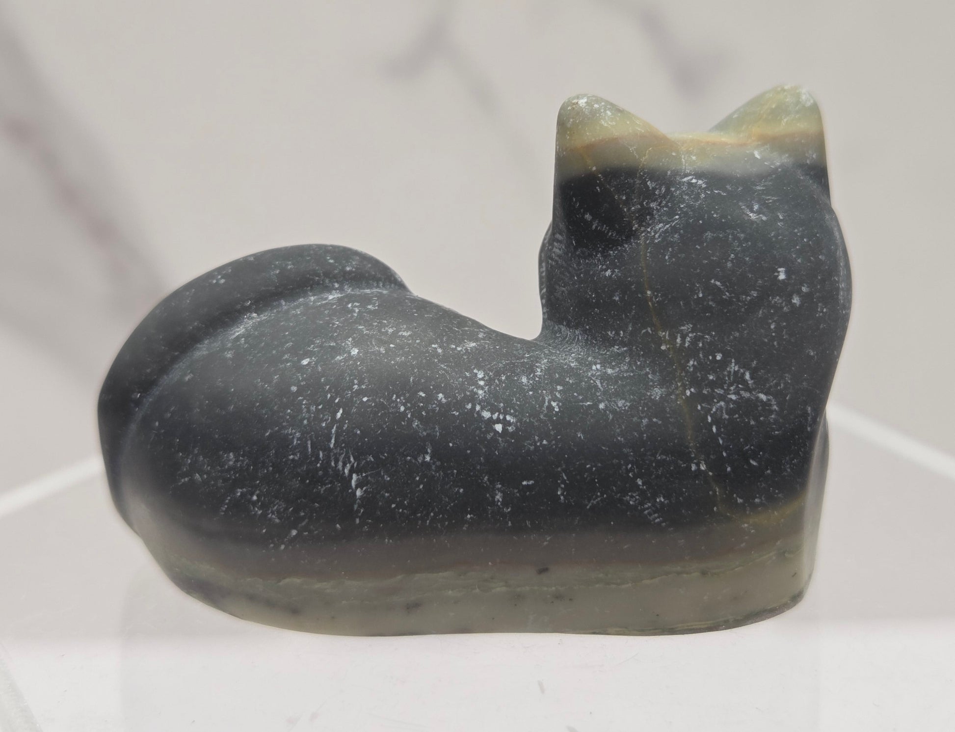 Jasper cat carving lying down an acrylic stand against a neutral background