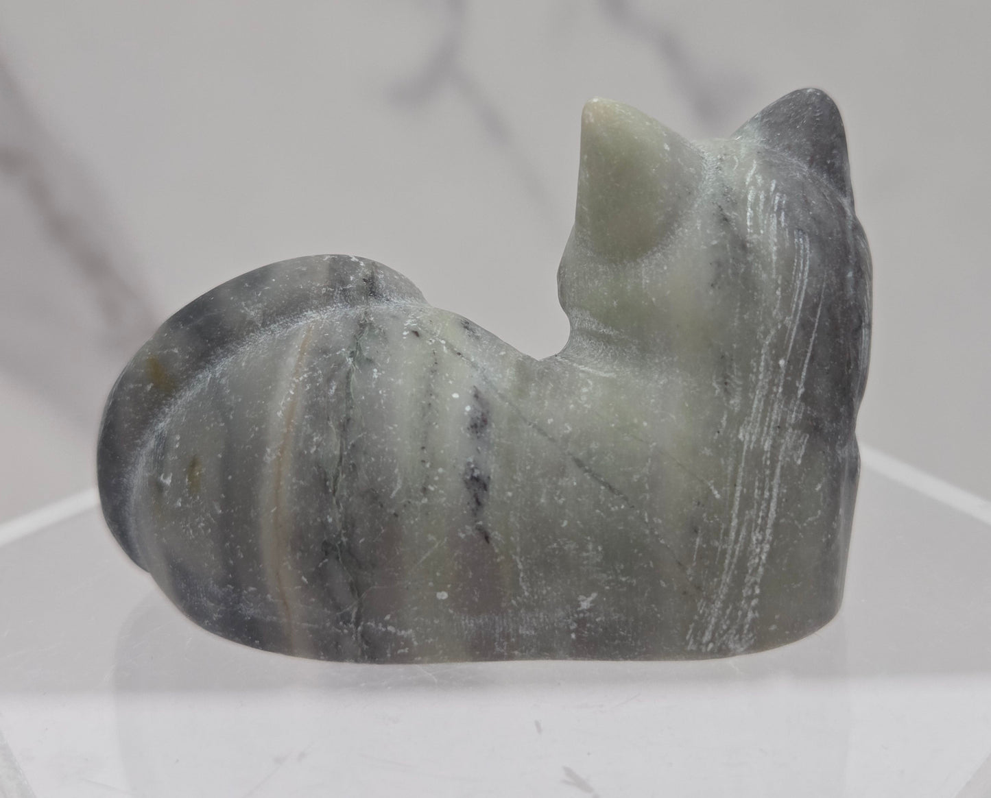 Jasper cat carving lying down an acrylic stand against a neutral background
