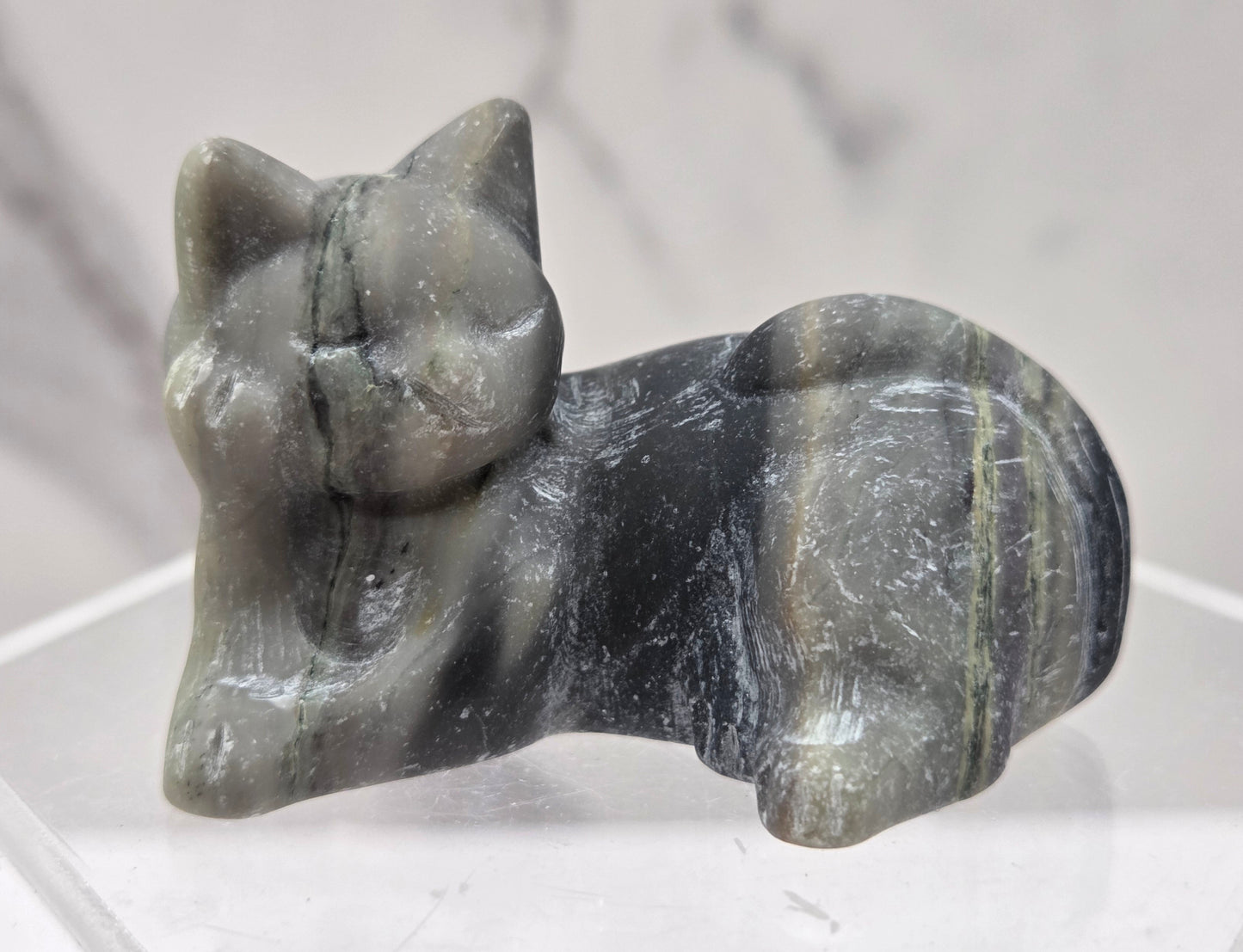 Jasper cat carving lying down an acrylic stand against a neutral background