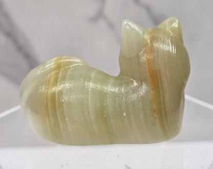 Afghan Jade cat carving lying down an acrylic stand against a neutral background