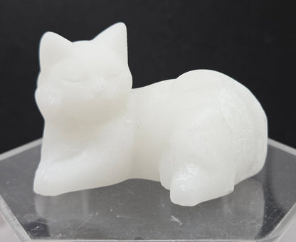 White Jade cat carving lying down an acrylic stand against a neutral background