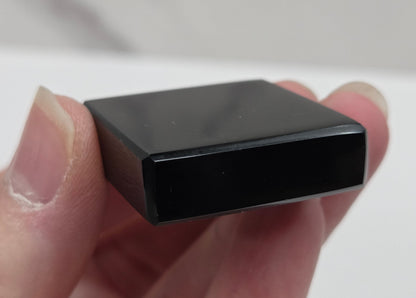 Hand holding a black rectangular object against a white background