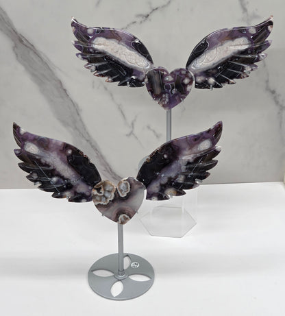 Black Flower Agate carved into wings and hearts on a silver stand against a white background.
