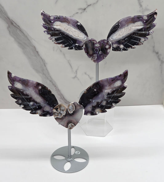 Black Flower Agate carved into wings and hearts on a silver stand against a white background.