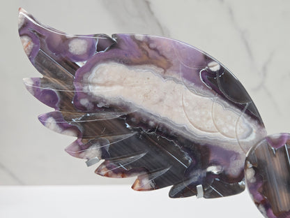 Black Flower Agate carved into wings and hearts on a silver stand against a white background.
