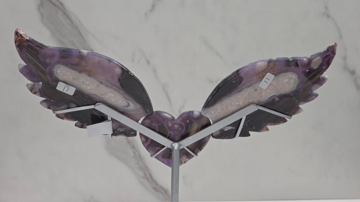 Black Flower Agate carved into wings and hearts on a silver stand against a white background.