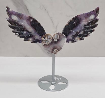 Black Flower Agate carved into wings and hearts on a silver stand against a white background.