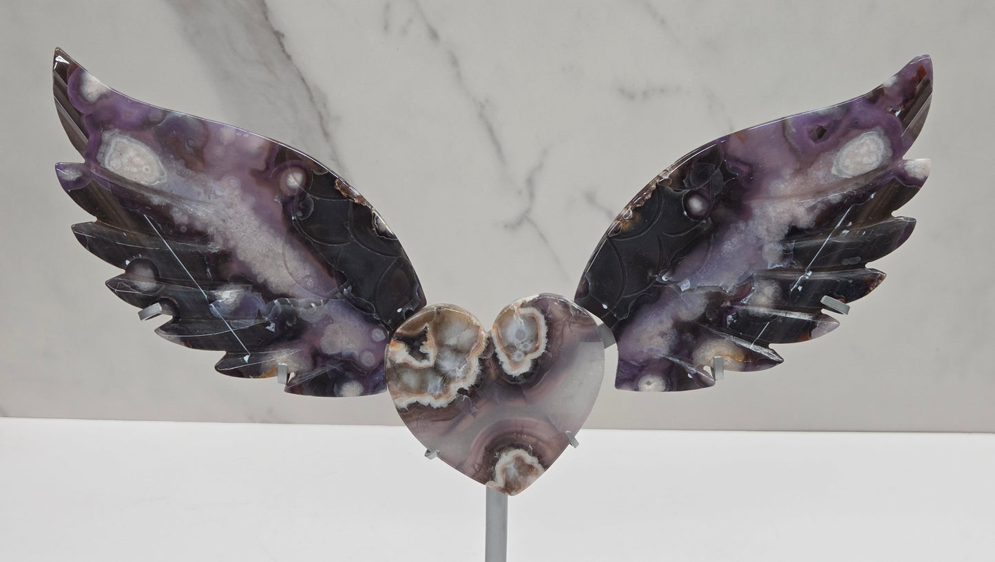 Black Flower Agate carved into wings and hearts on a silver stand against a white background.
