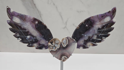 Black Flower Agate carved into wings and hearts on a silver stand against a white background.