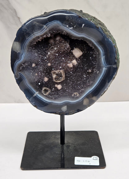 Amethyst and Agate round geode with white calcite inclusions on a black stand against a white background