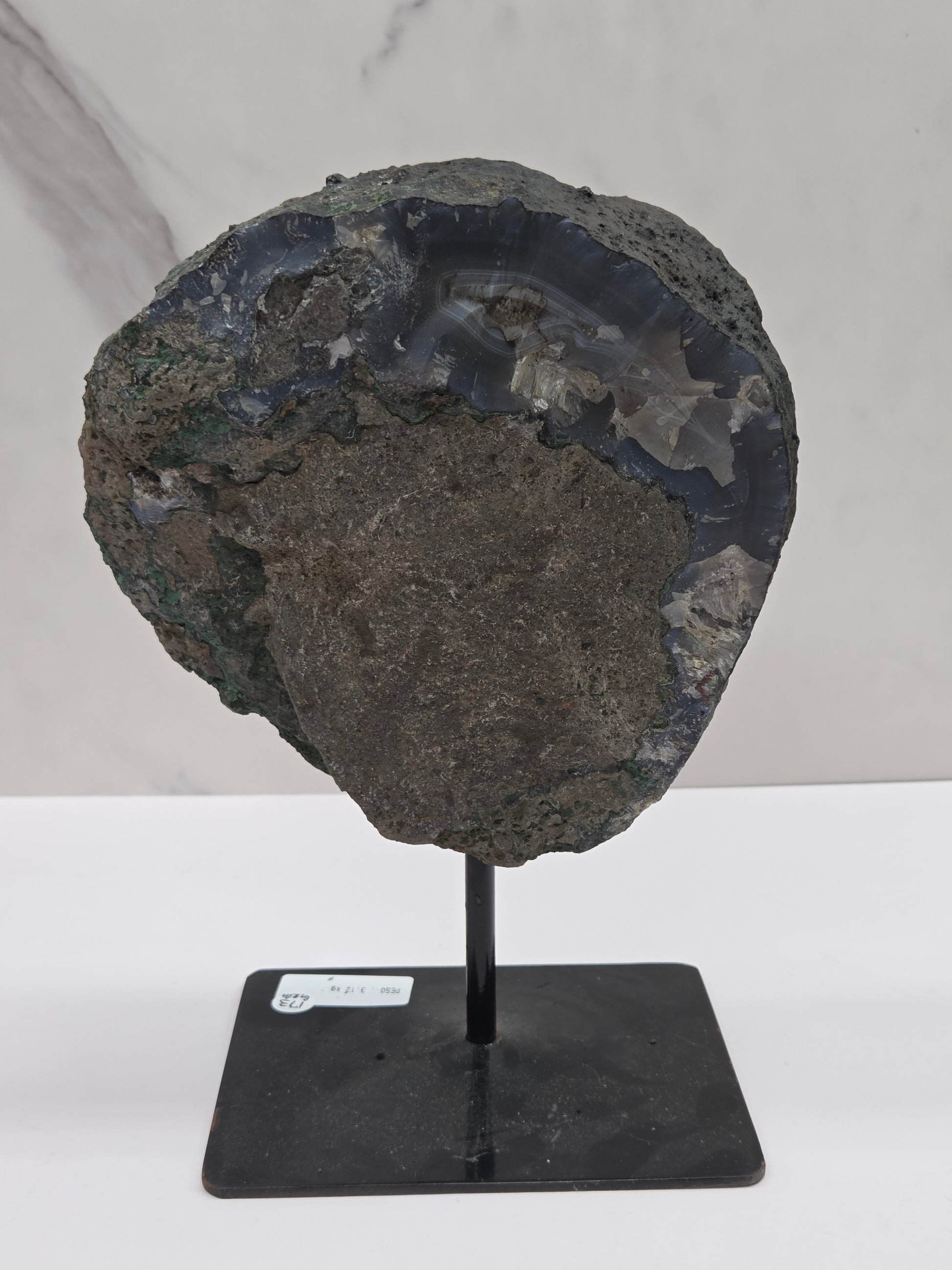 Back side of an Amethyst and Agate round geode on a black stand against a white background