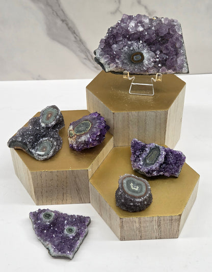 Amethyst with Stalactite eye specimens on a wood stand against a white background