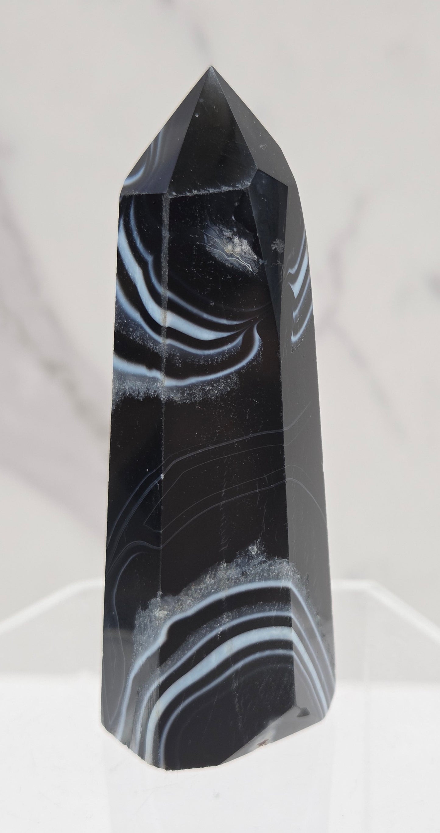 Black Agate tower with quartz and white bands on a clear stand against a white background