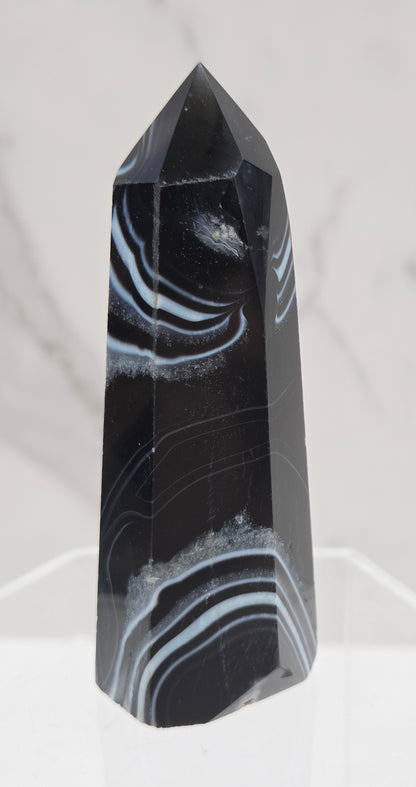 Black Agate tower with quartz and white bands on a clear stand against a white background