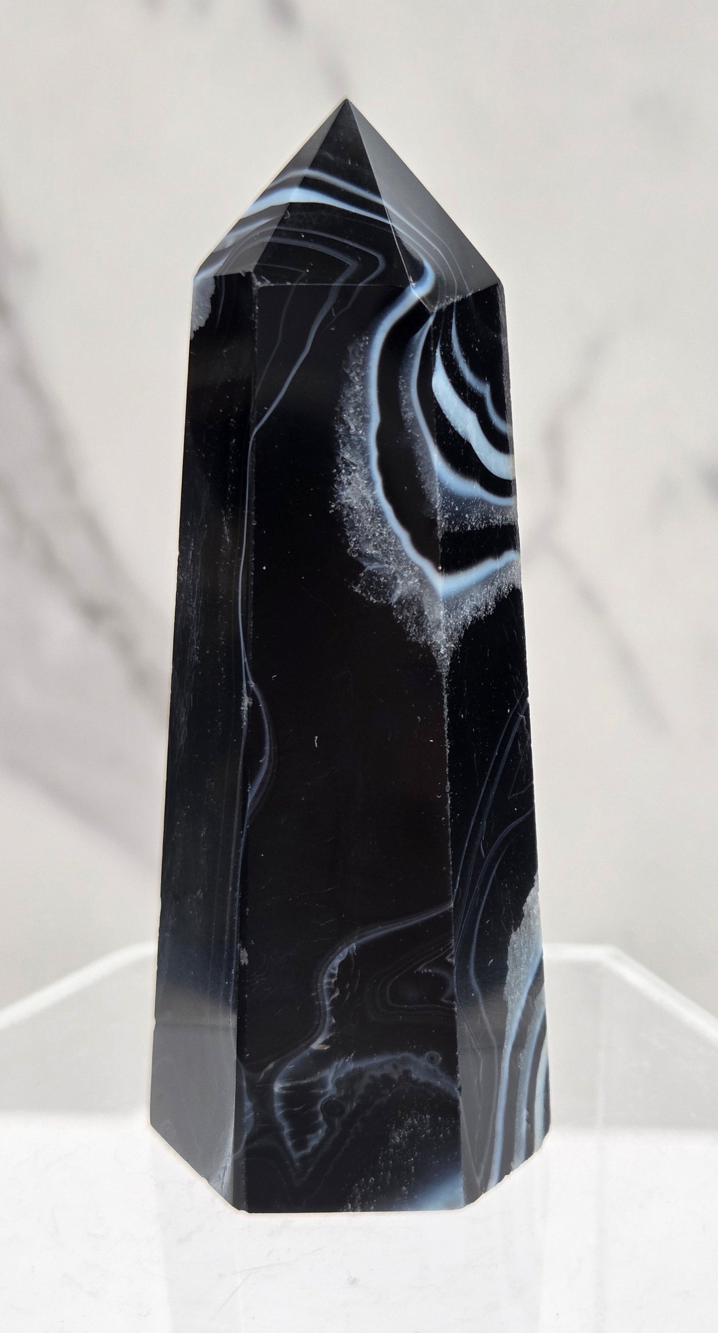Black Agate tower with quartz and white bands on a clear stand against a white background