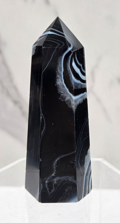 Black Agate tower with quartz and white bands on a clear stand against a white background